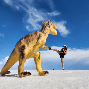A person kicking a toy dinosaur

Description automatically generated